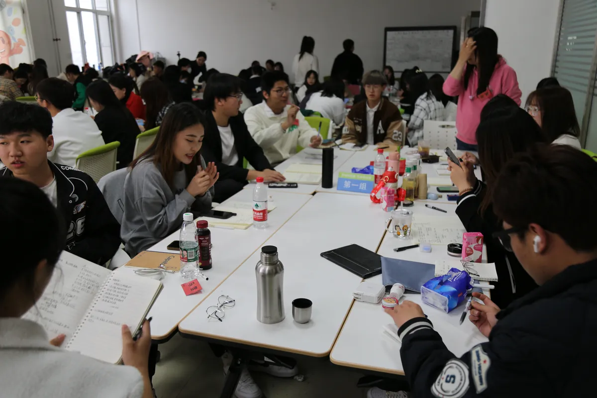In-house team learning session: Chinese cross-border agents in a circle workshop format, taking notes on import compliance, customs HS codes and live commerce scripting.